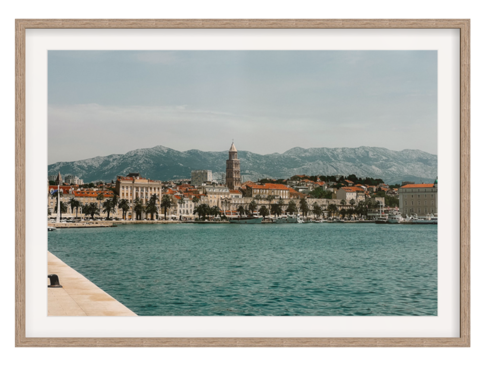 Cityscape with a prominent tower by a body of water, framed as a photograph. Split landscape hazel frame with border