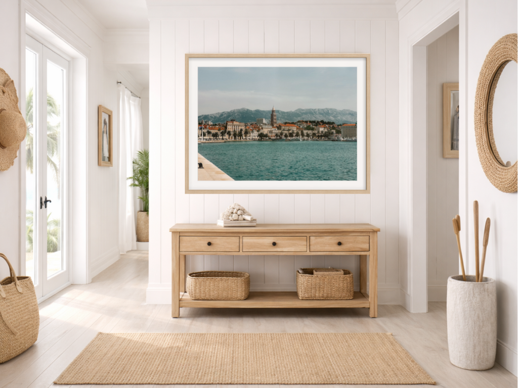 Nautical-themed room with a framed picture of a coastal scene, wooden console table, and decorative items.