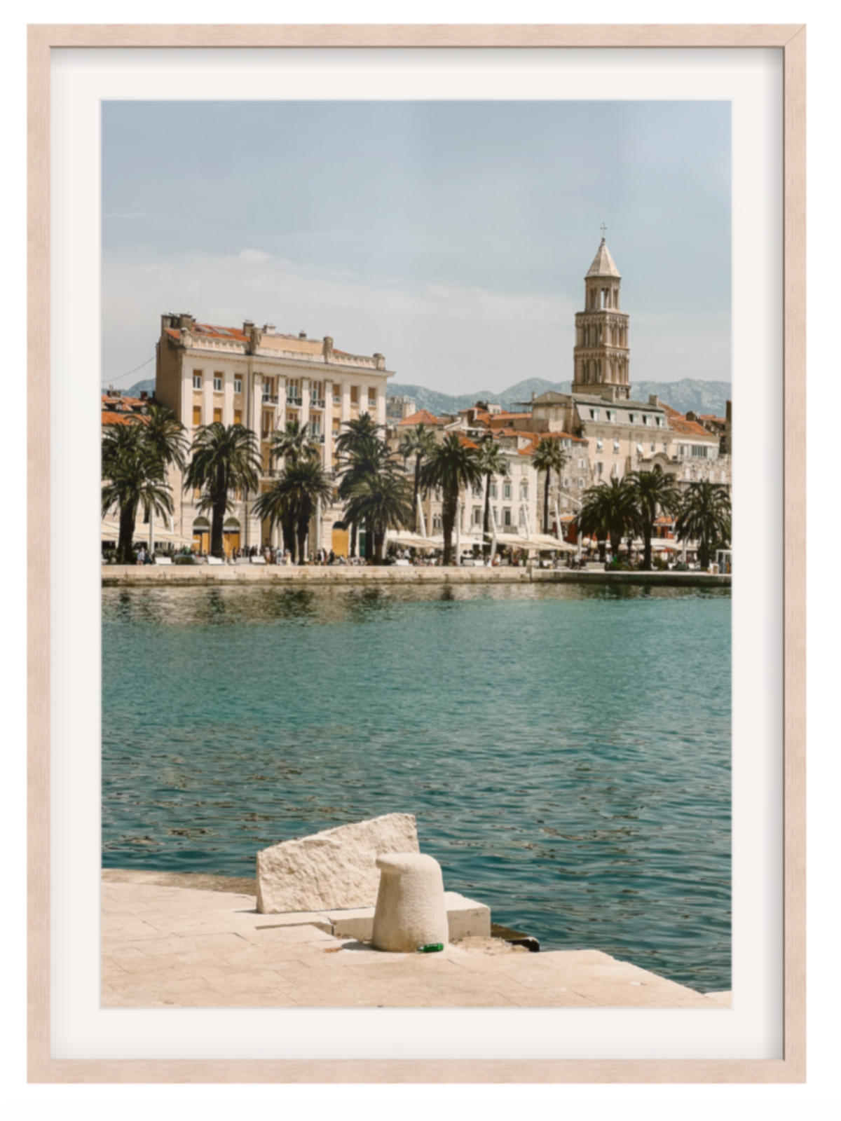 Framed photograph of a coastal scene with buildings and palm trees. Split light oak frame with border