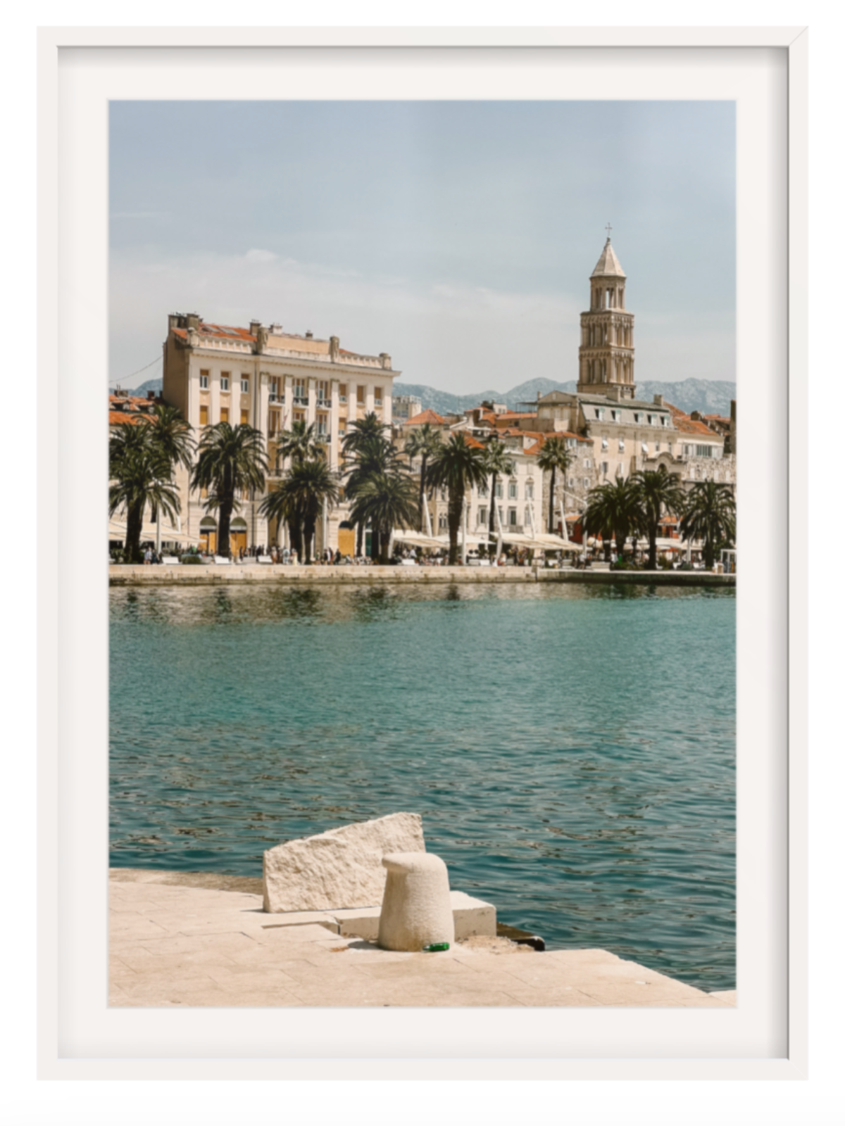 Framed photograph of a coastal cityscape with a clock tower and waterfront. Split white frame with border