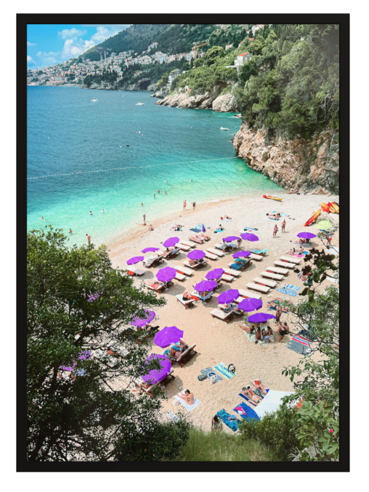Beach scene with purple umbrellas and people near a clear blue sea.