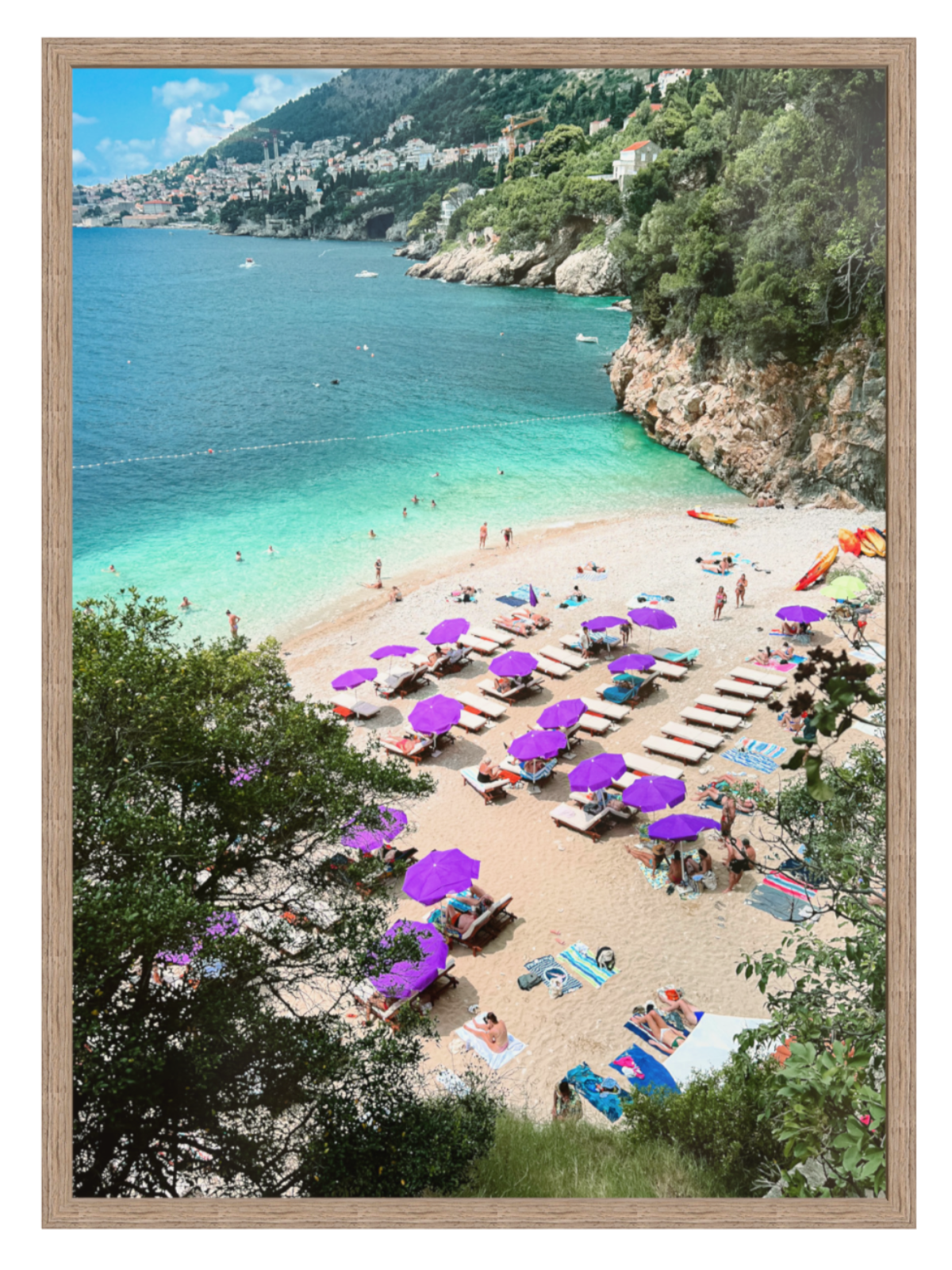 Beach scene with purple umbrellas and people on a sandy shore with turquoise water and greenery.