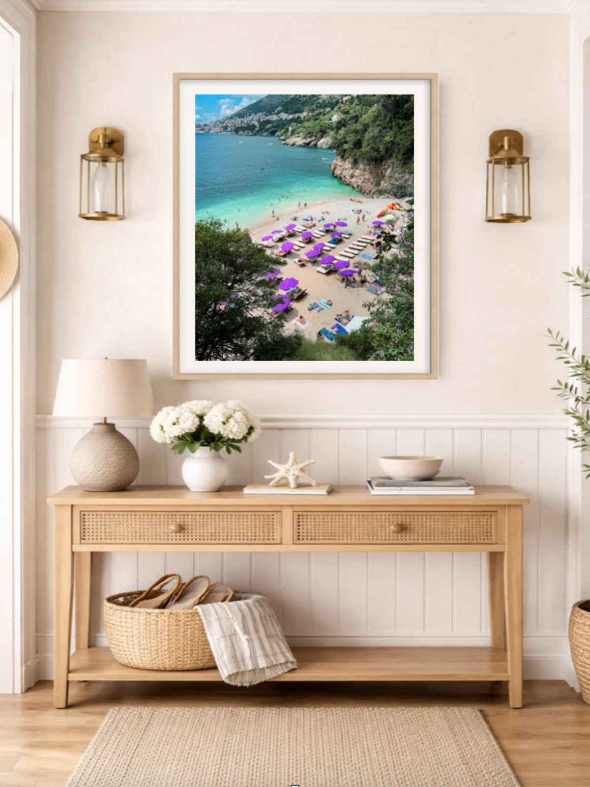 Framed beach scene print above a wooden console table with decorative items.