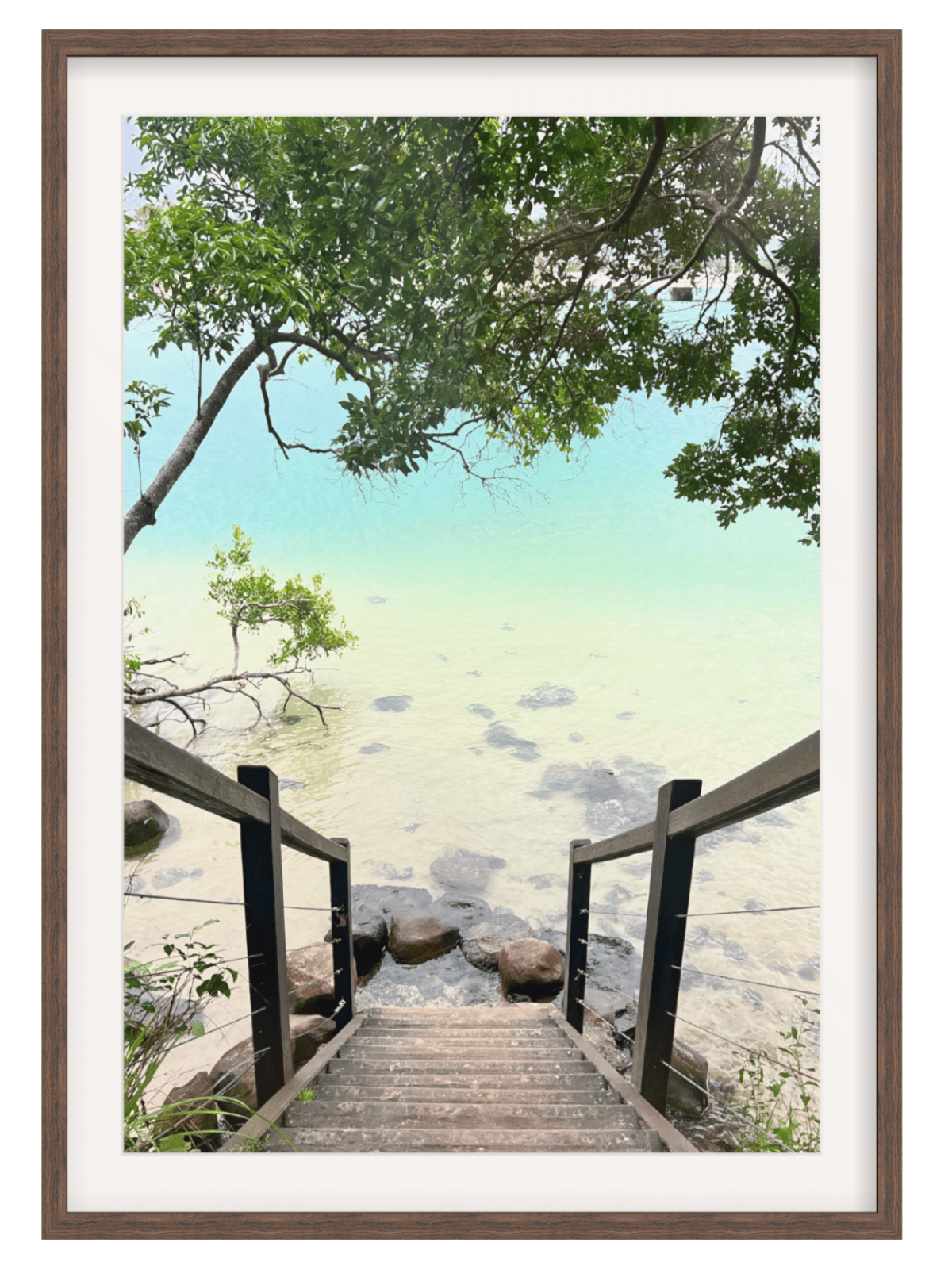 Wooden staircase leading to a beach with trees and rocks, framed in brown.