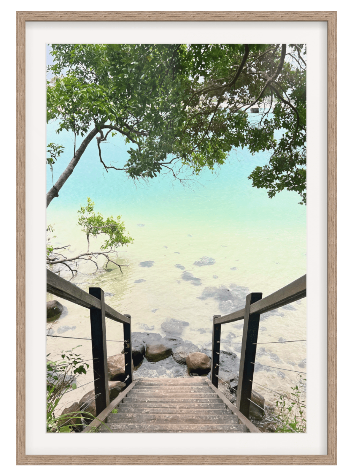 Wooden staircase leading to a beach with trees and water in the background, framed in white.