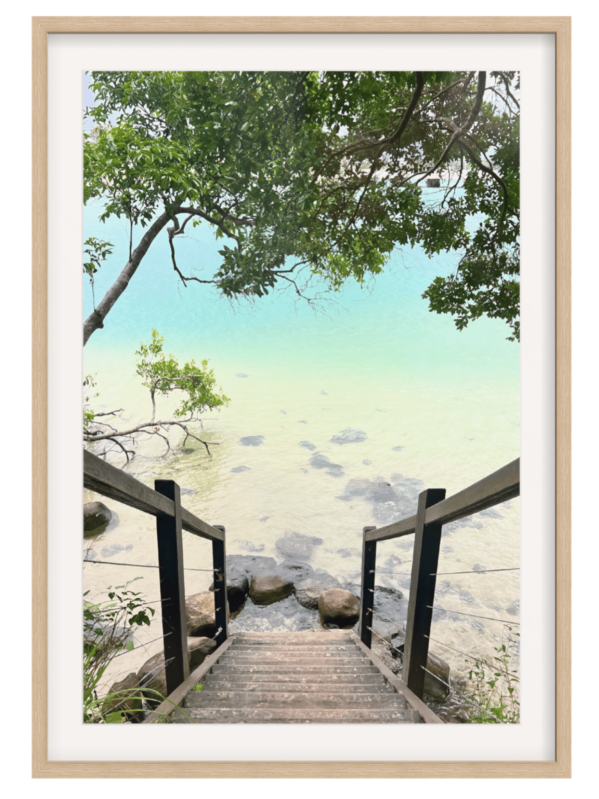 Wooden staircase leading to a serene beach scene with trees and rocks.