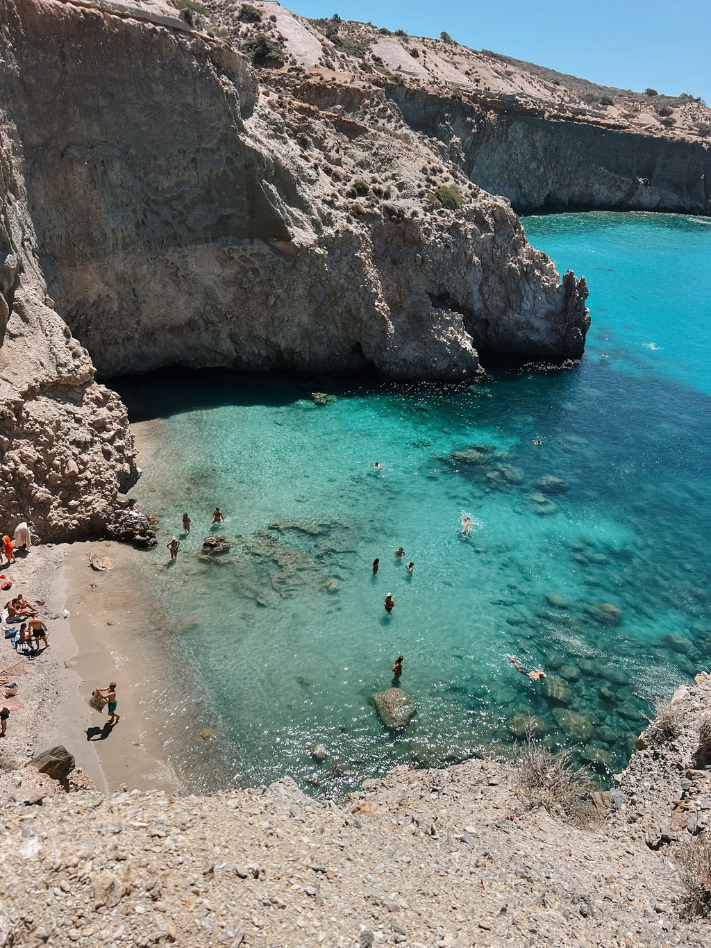 Beach with clear blue water and rocky cliffs
