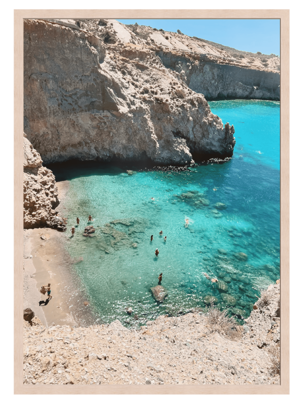 Cove with clear blue water and rocky cliffs, people swimming and enjoying the beach.