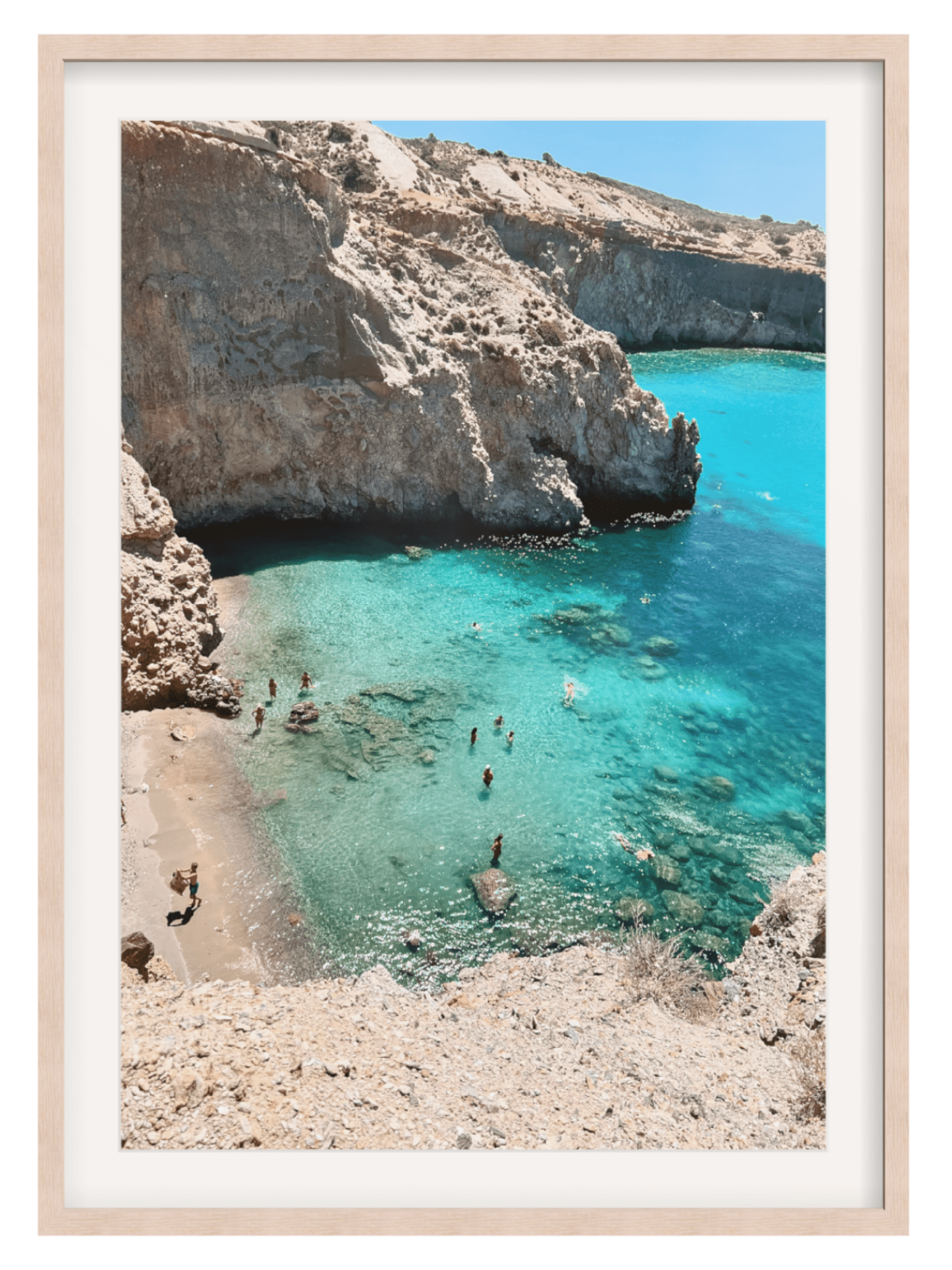 Framed photograph of a rocky coastline with clear blue water and people swimming.