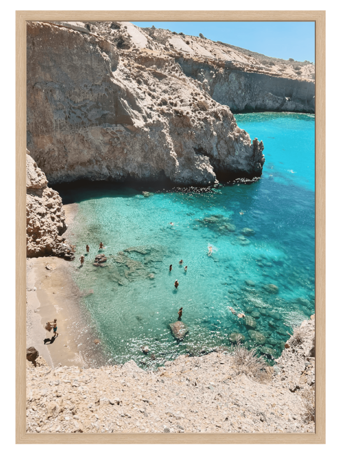 Cove with clear blue water and rocky cliffs, people swimming and enjoying the beach.
