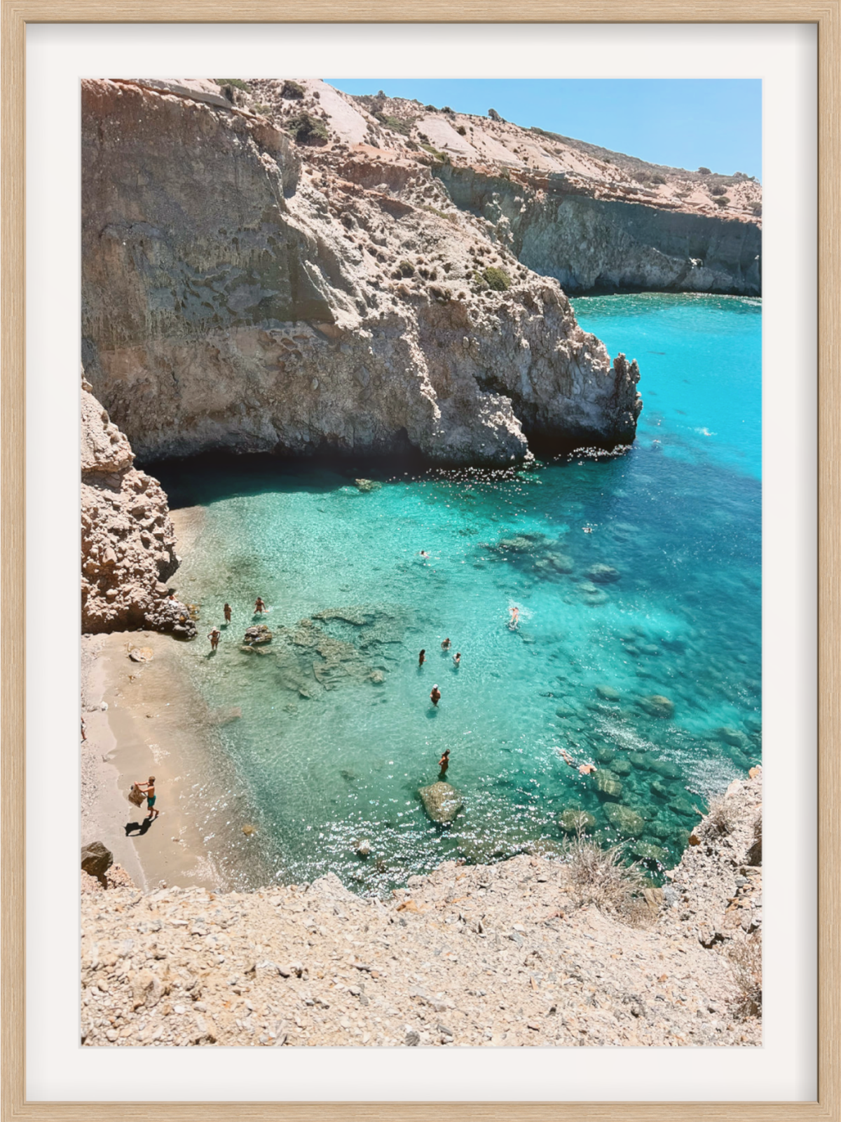 Cove with clear blue water and rocky cliffs, people swimming.