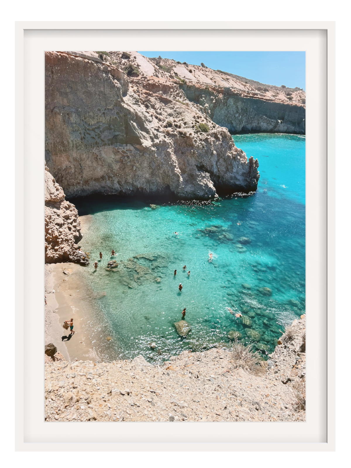 Cove with clear blue water and rocky cliffs, people swimming.