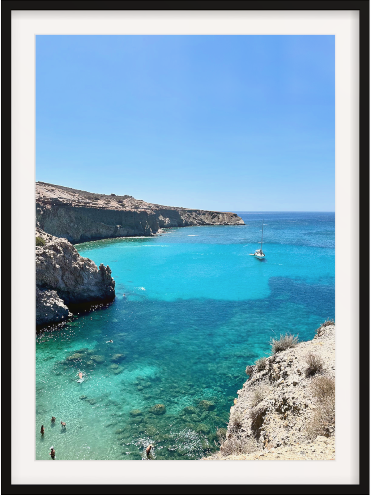 Turquoise sea with a sailboat and people near cliffs under a clear blue sky.