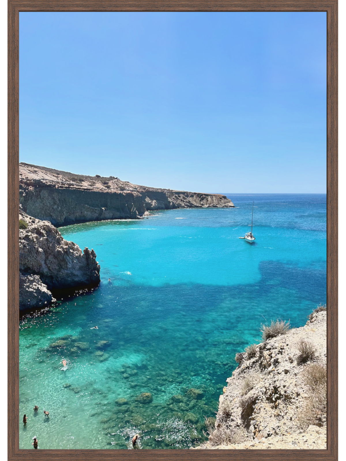 Framed photograph of a coastal scene with clear blue water and rocky cliffs.