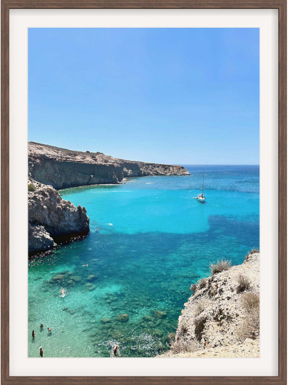 Framed photograph of a coastal scene with clear blue water and rocky cliffs.