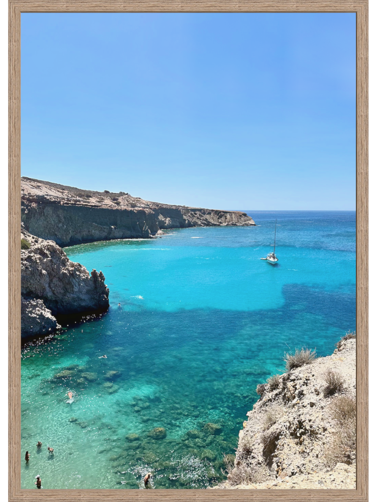Framed photograph of a coastal scene with clear blue water and cliffs.