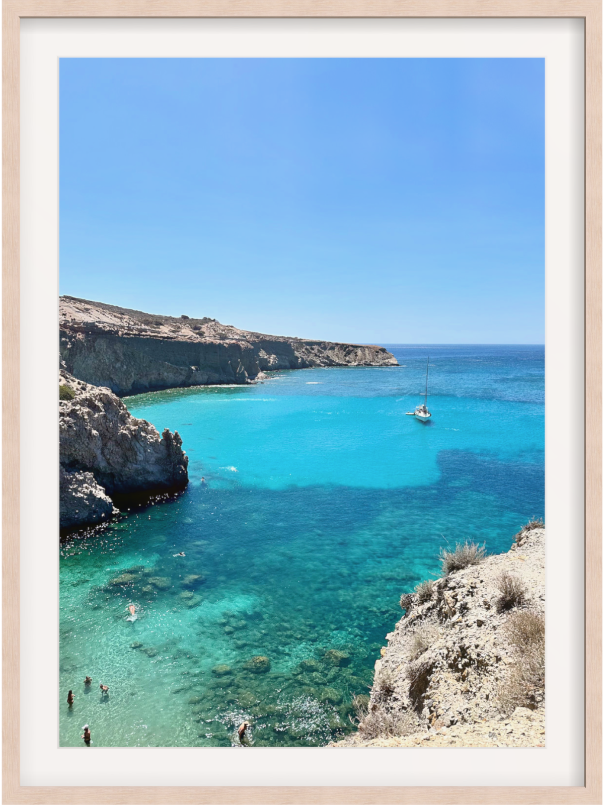 Framed photograph of a coastal scene with clear blue water and cliffs.