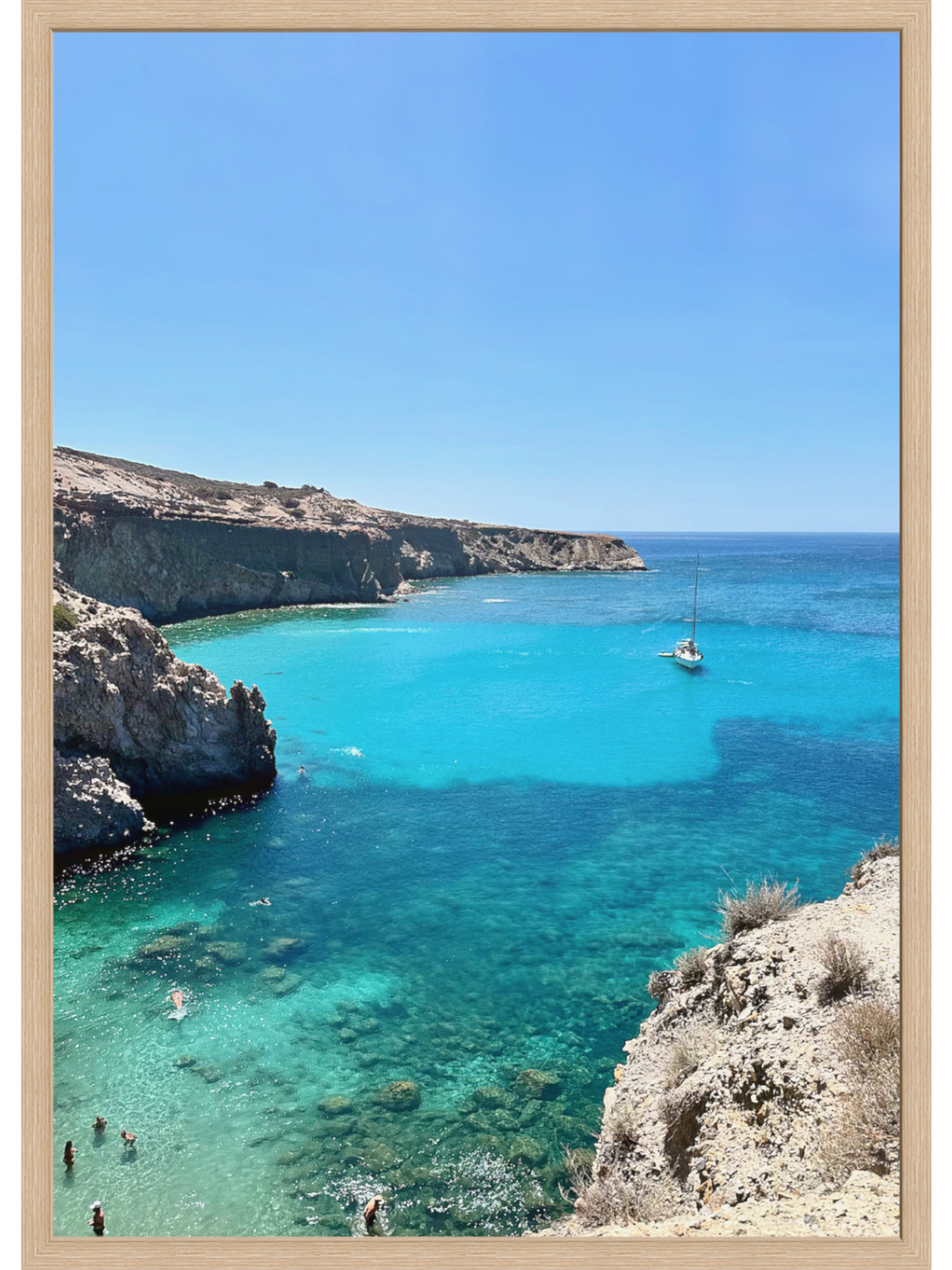 Cove with clear blue water and rocky cliffs under a bright blue sky.