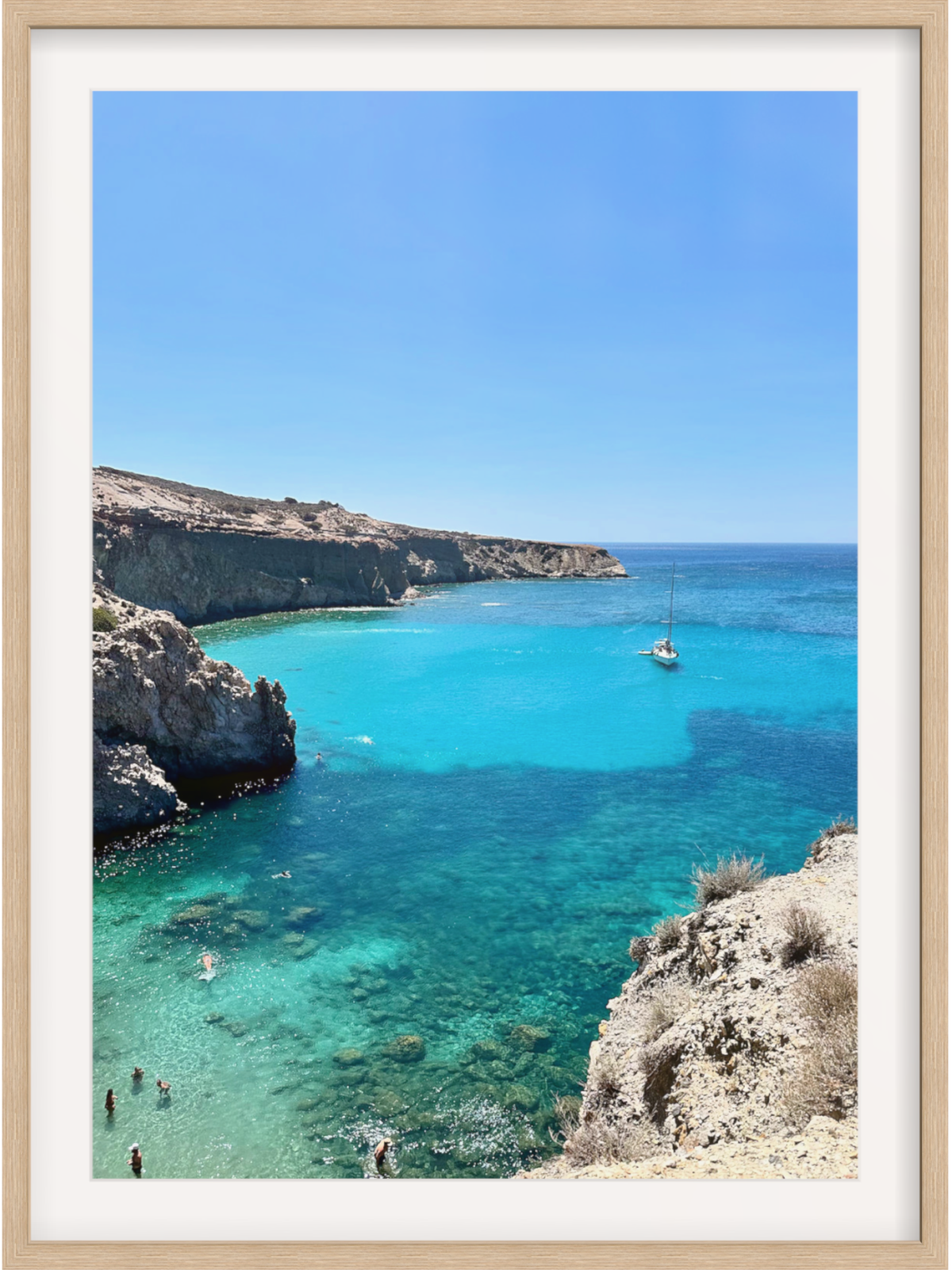 Framed photograph of a scenic coastal view with clear blue water and rocky cliffs.