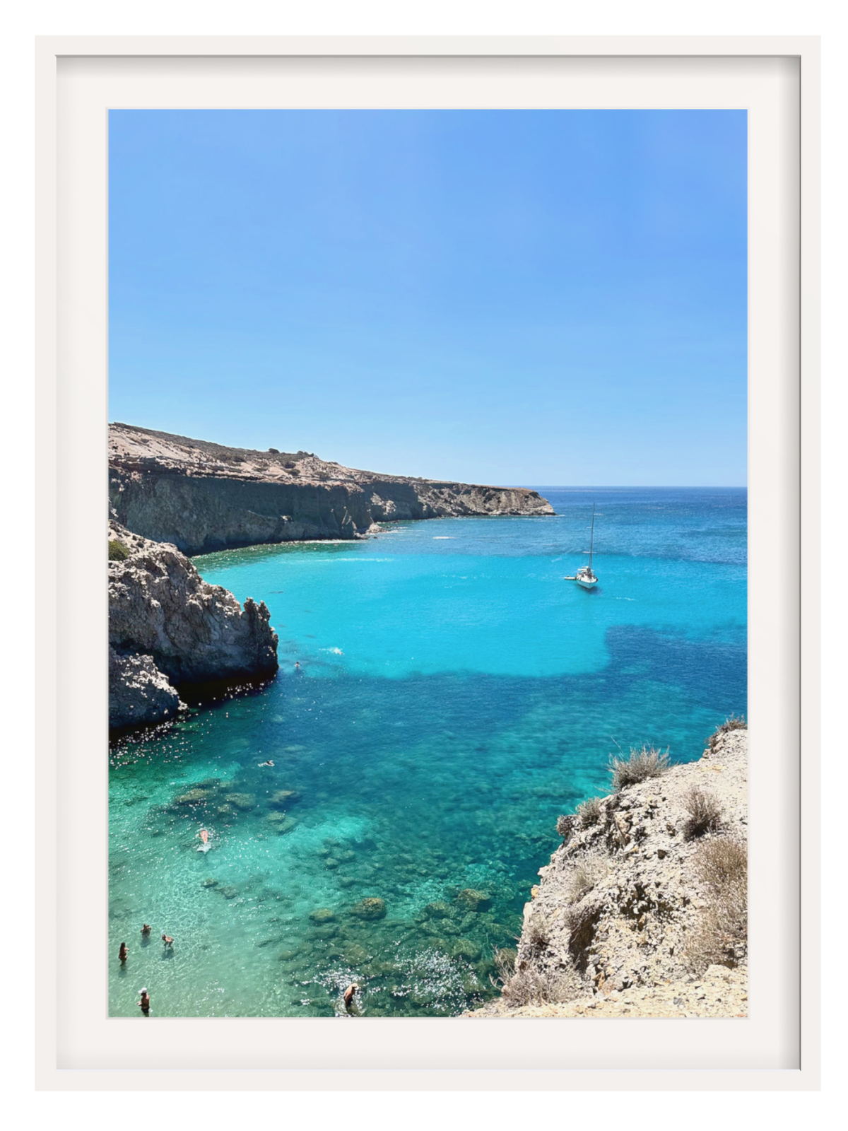 Coastal scene with clear blue water, rocky cliffs, and a sailboat.