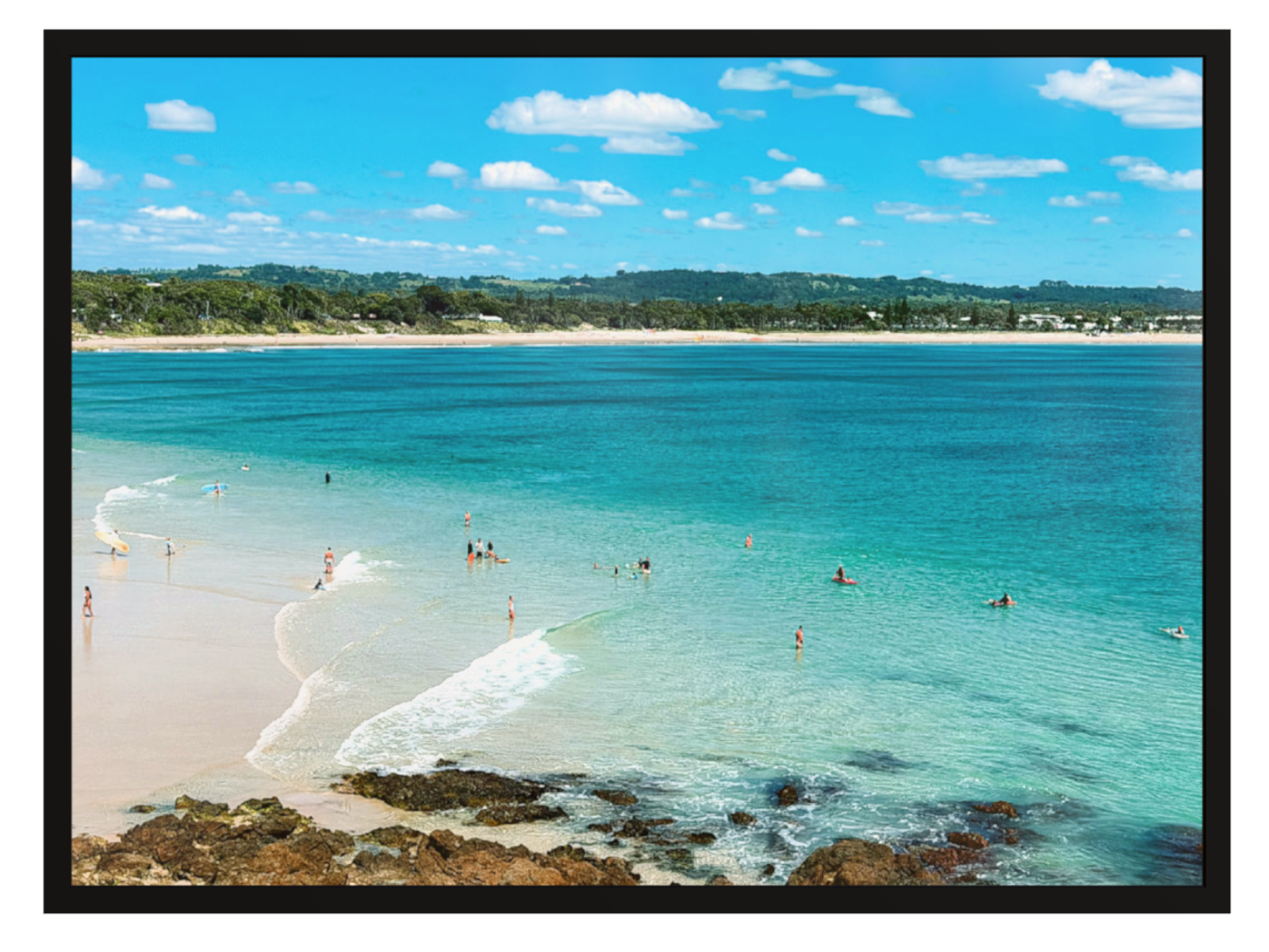 Beach scene with clear blue water and people enjoying the sun.