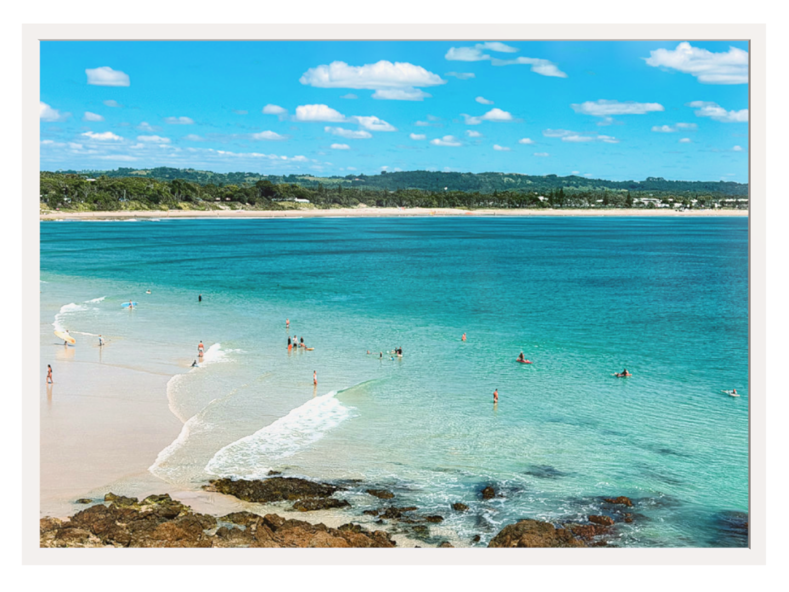 Beach scene with clear blue water and people enjoying the sun.