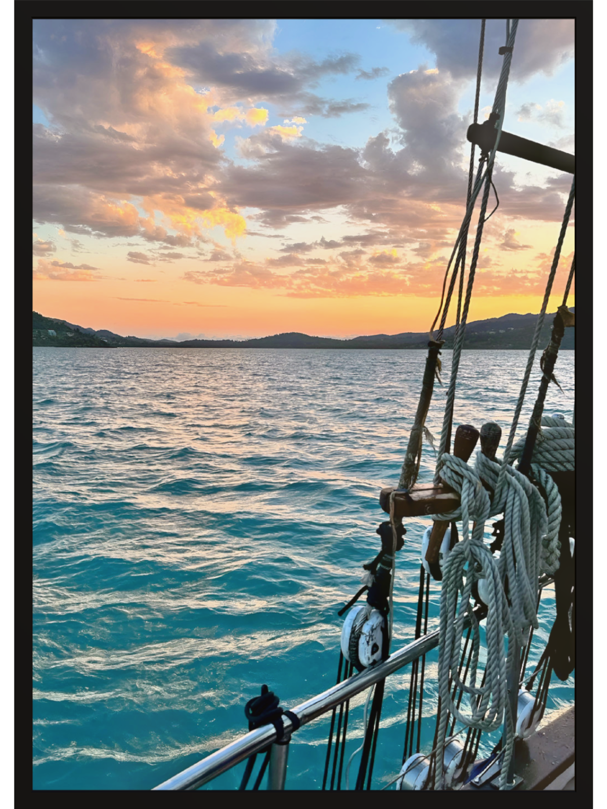 Sailing scene with sunset over water and ship's rigging.