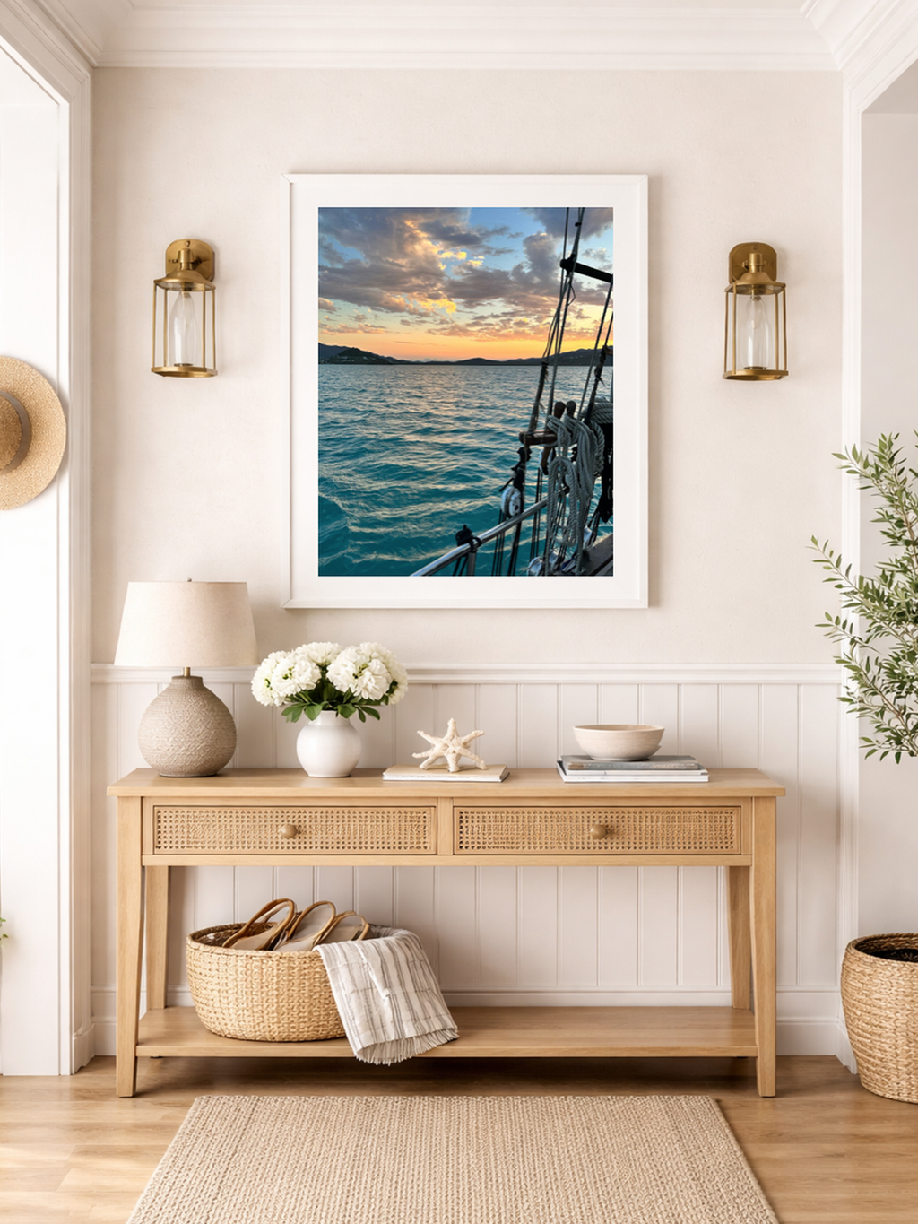 Nautical-themed wall art above a wooden console table in a room with a lamp, flowers, and decorative items.