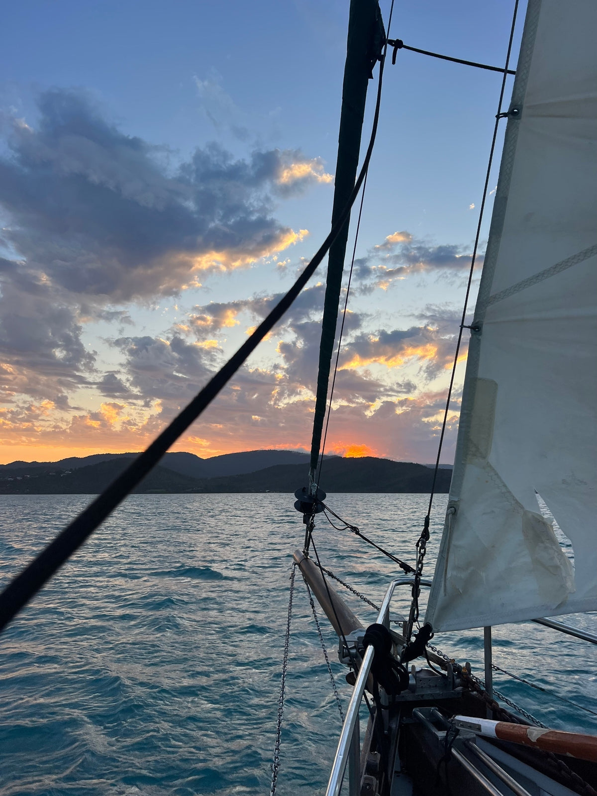 Sailing boat with sunset and mountains in the background