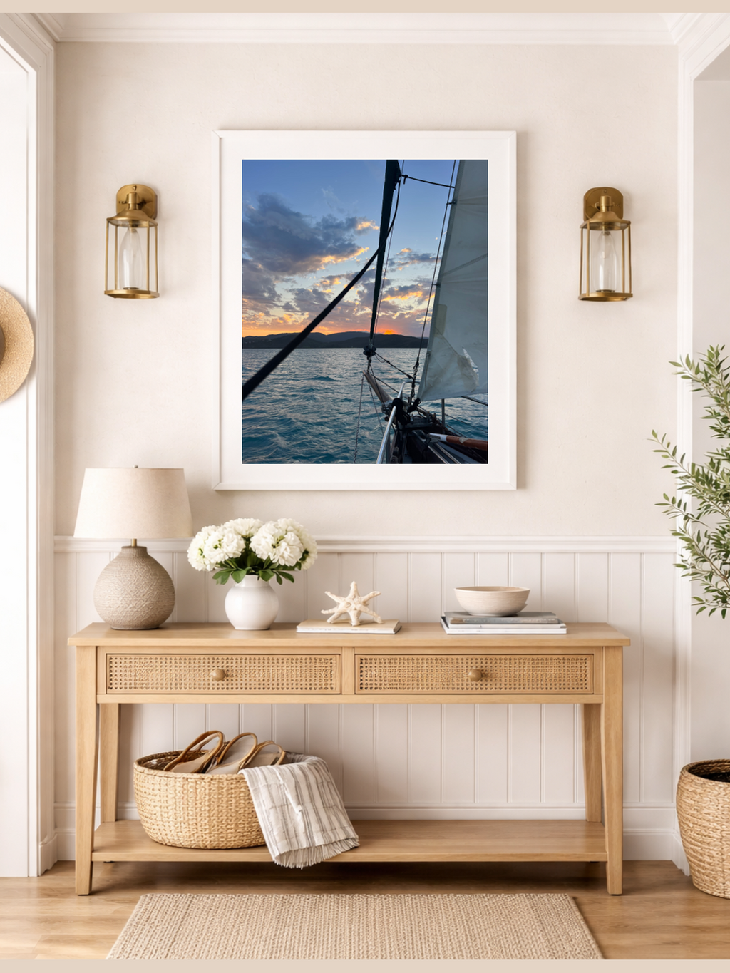 Framed photograph of a sailboat on a wall above a wooden console table with decorative items.