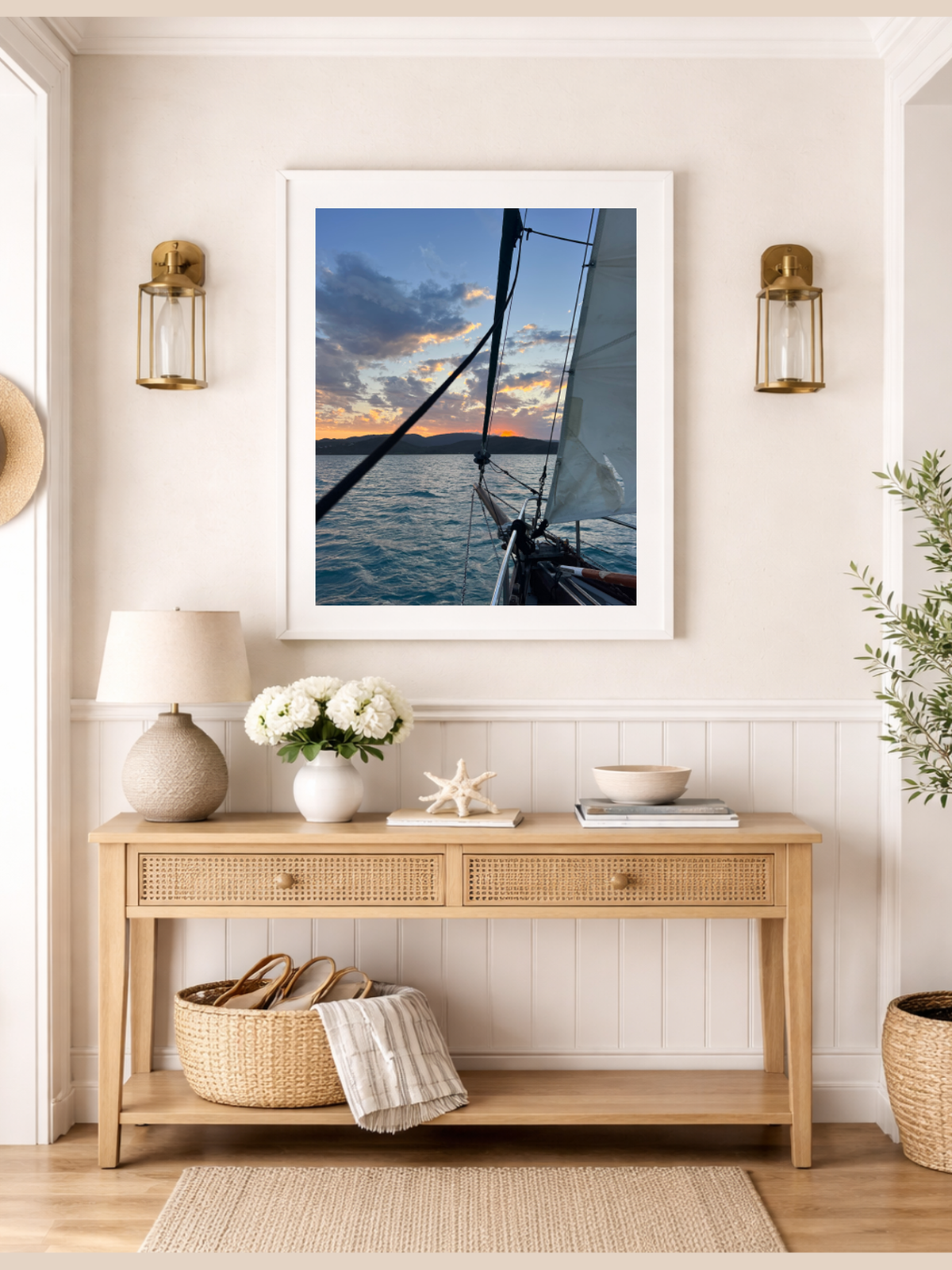 Framed photograph of a sailboat on a wall above a wooden console table with decorative items.