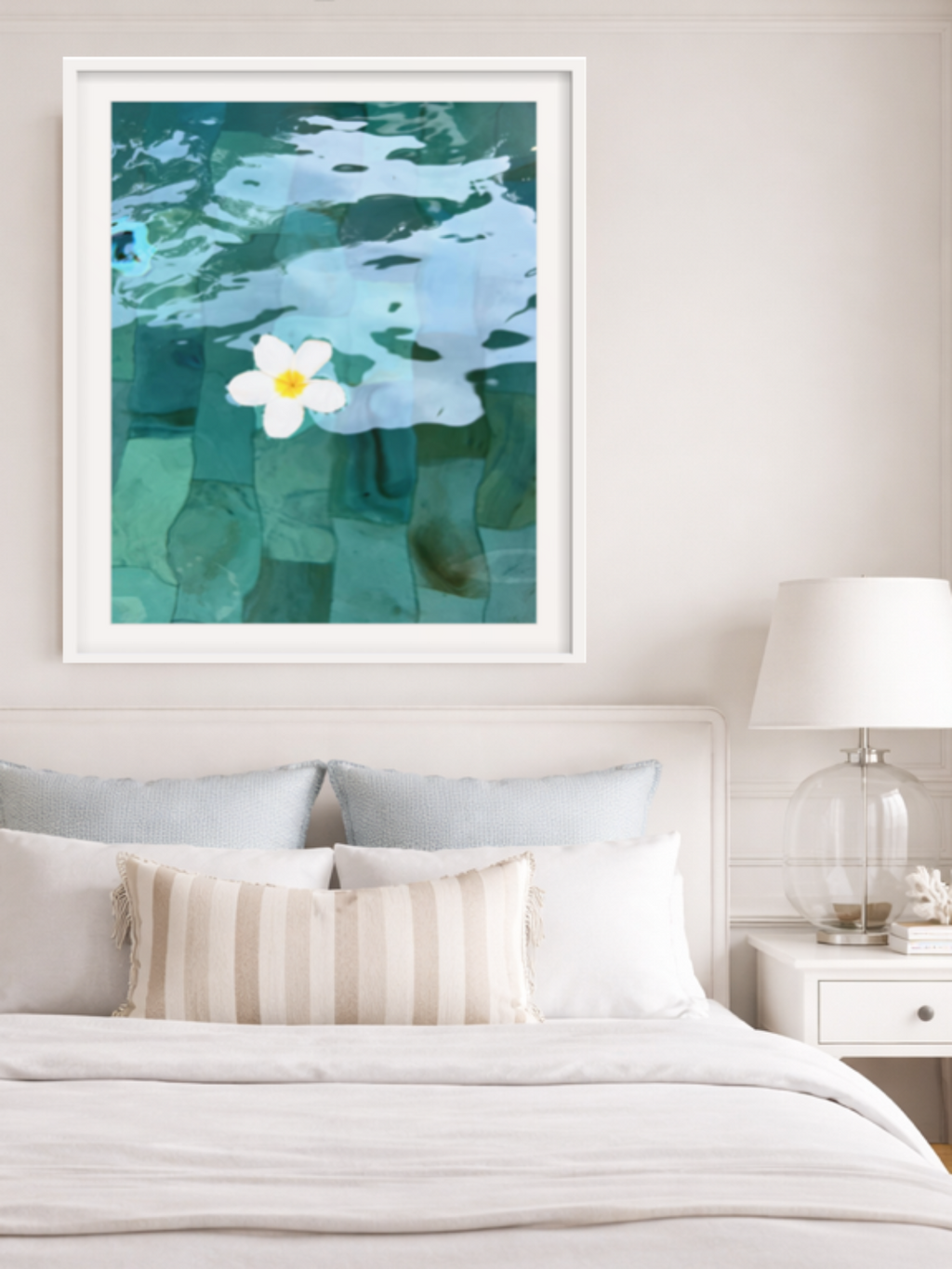 Framed artwork of a flower in water above a bed in a bedroom setting.