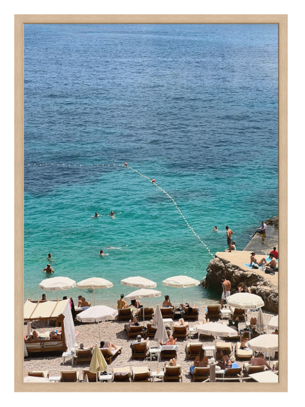 oak Framed photograph of a beach scene with people, umbrellas, and lounge chairs.