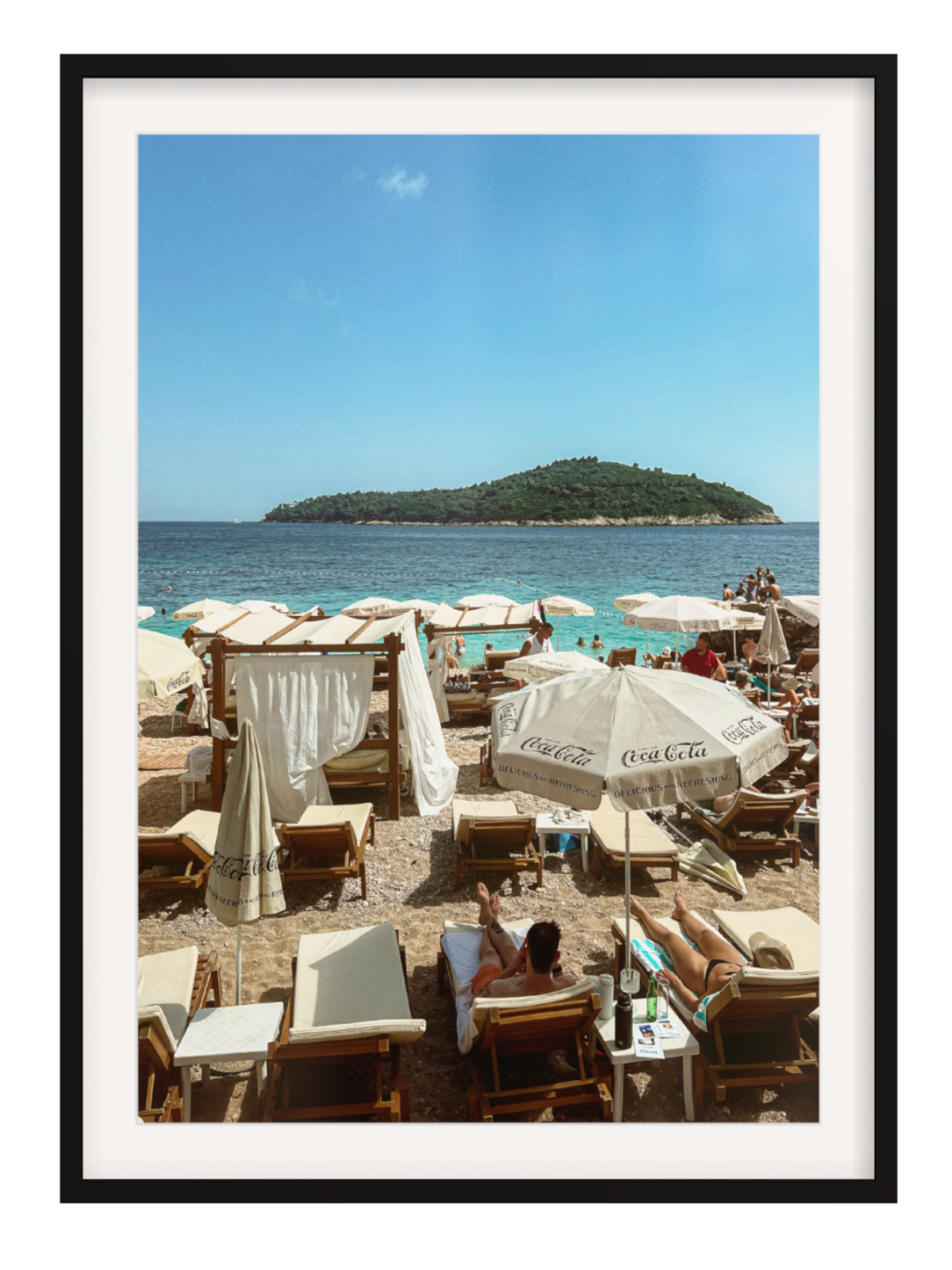 Beach scene with people, chairs, and Coca-Cola umbrellas under a clear blue sky.