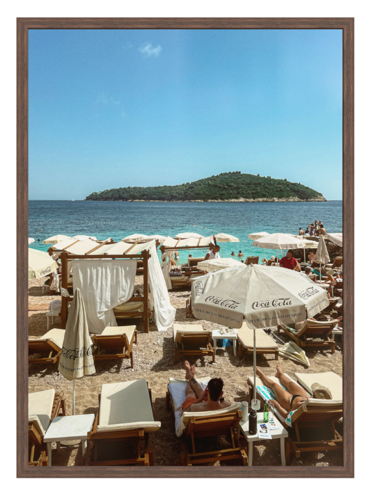 Beach scene with lounge chairs, umbrellas, and a view of an island.