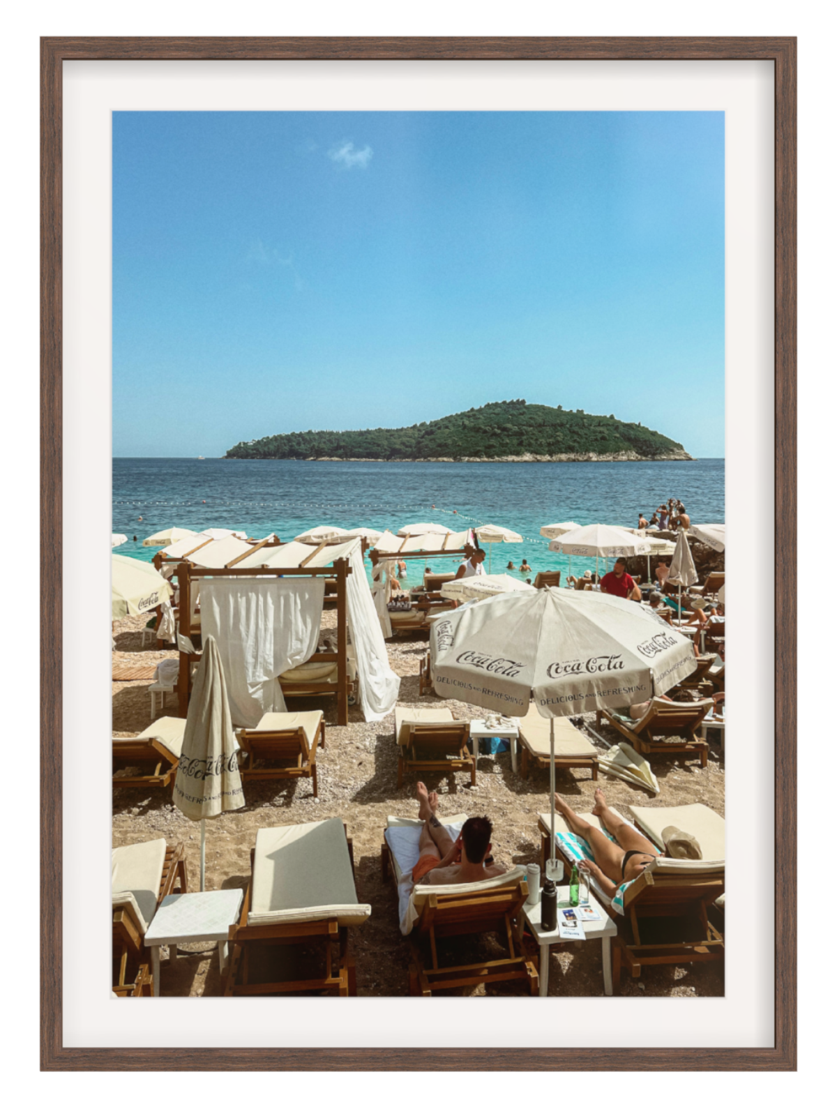 Beach scene with people under umbrellas and a view of an island.