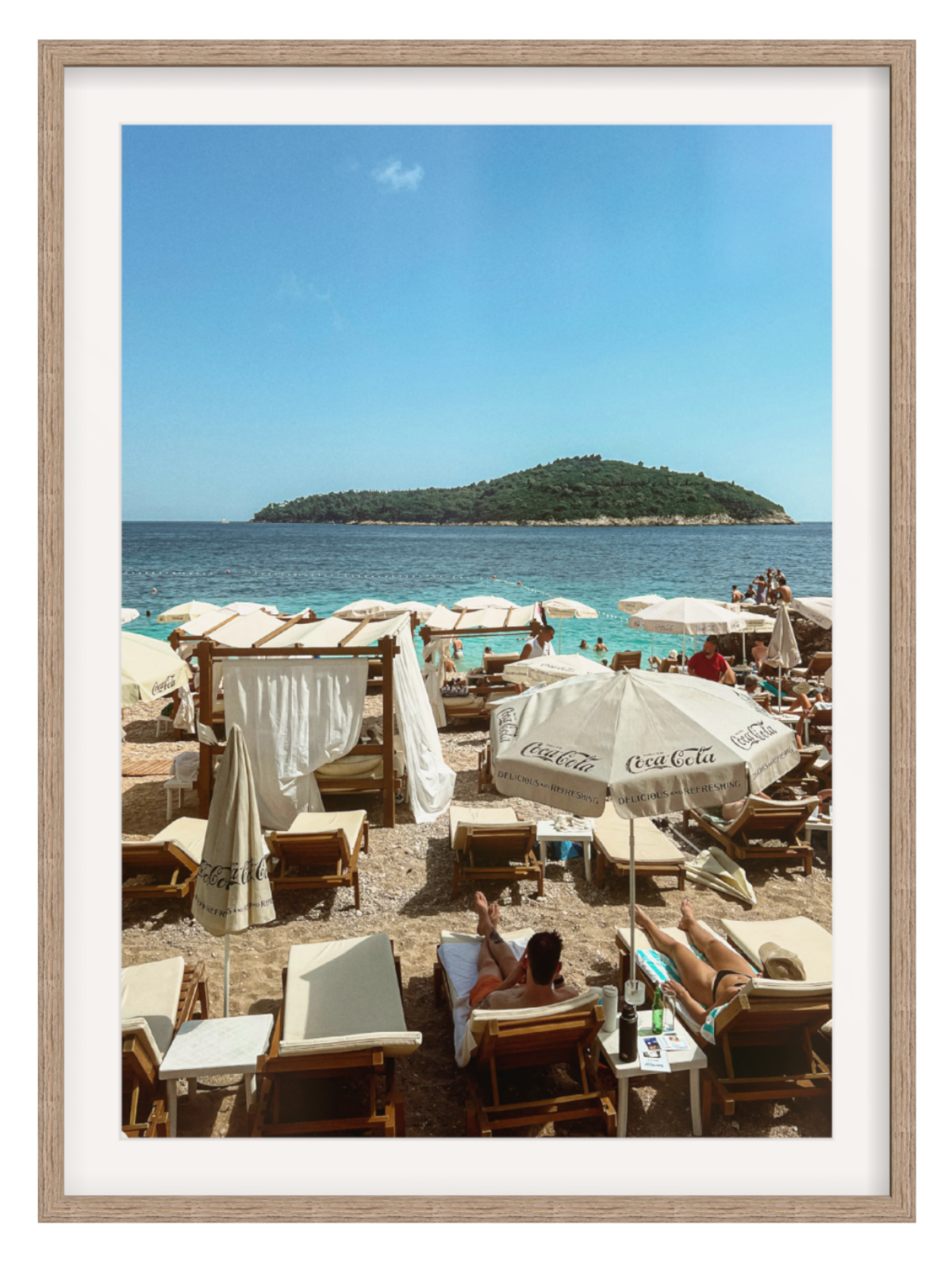 Beach scene with people, umbrellas, and a clear blue sky.