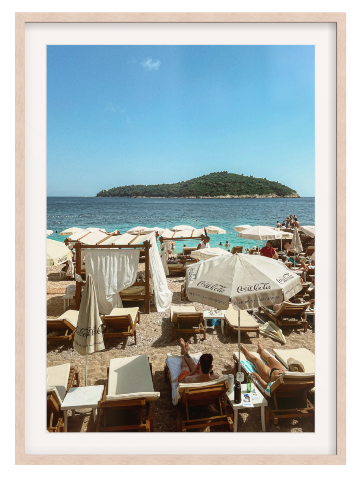 Beach scene with people under Coca-Cola umbrellas, framed picture.
