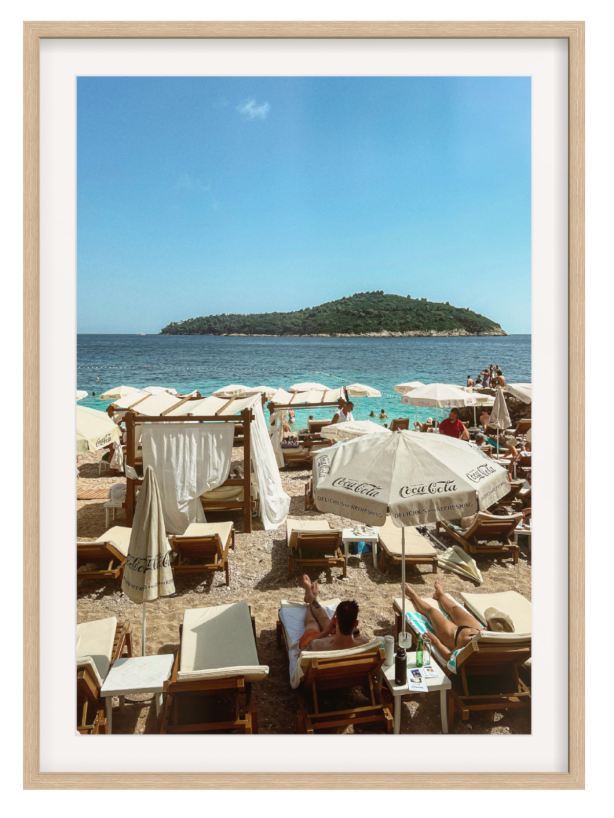 Beach scene with people under umbrellas and chairs, framed with a wooden border.