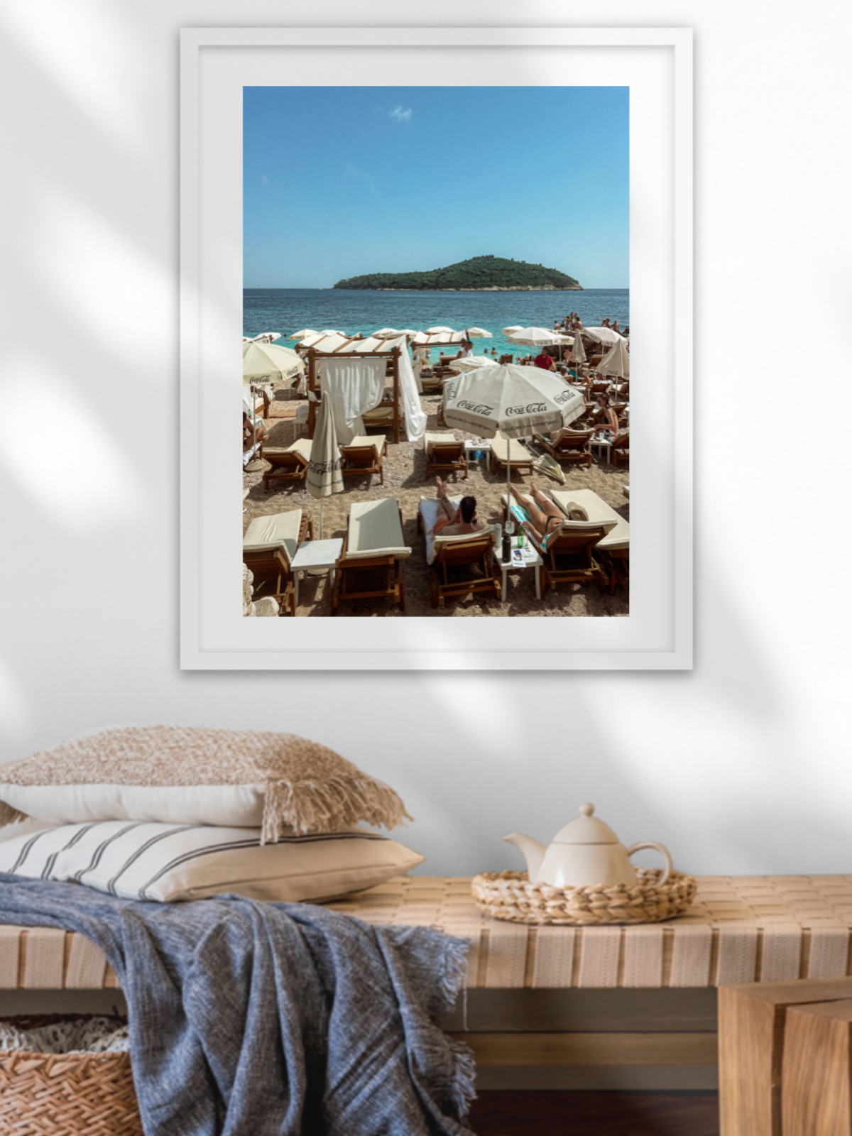 Framed photograph of a beach scene on a wall above a wooden console table.