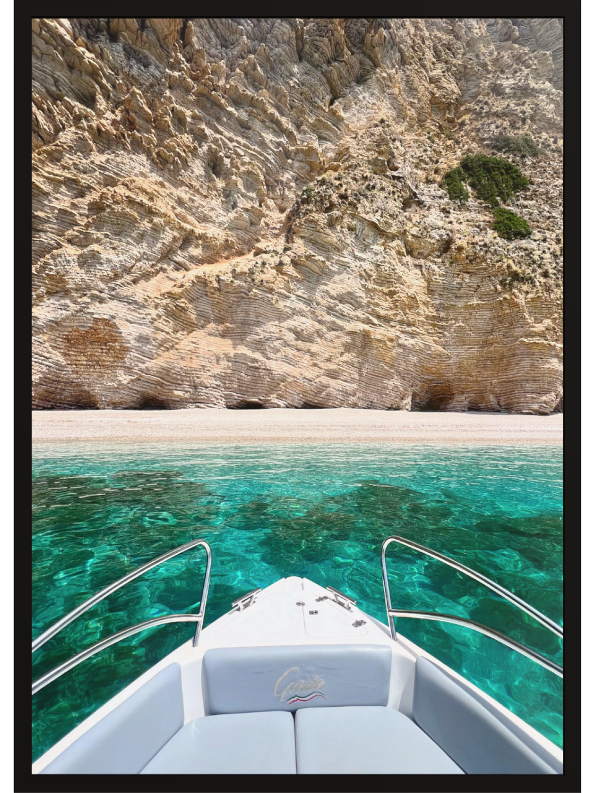 Boat on clear blue water with a rocky cliff in the background