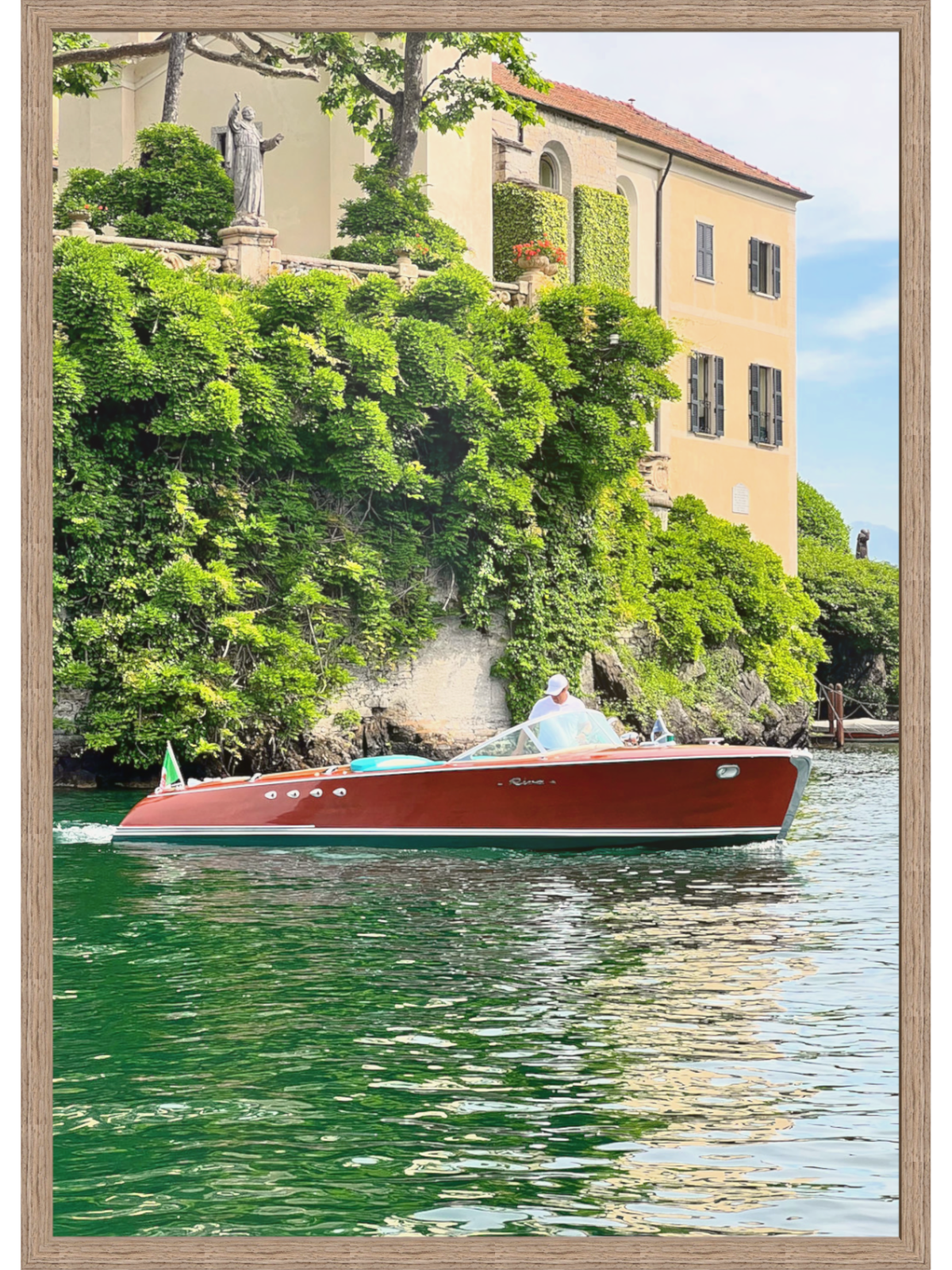 Red boat on a canal with a building and greenery in the background