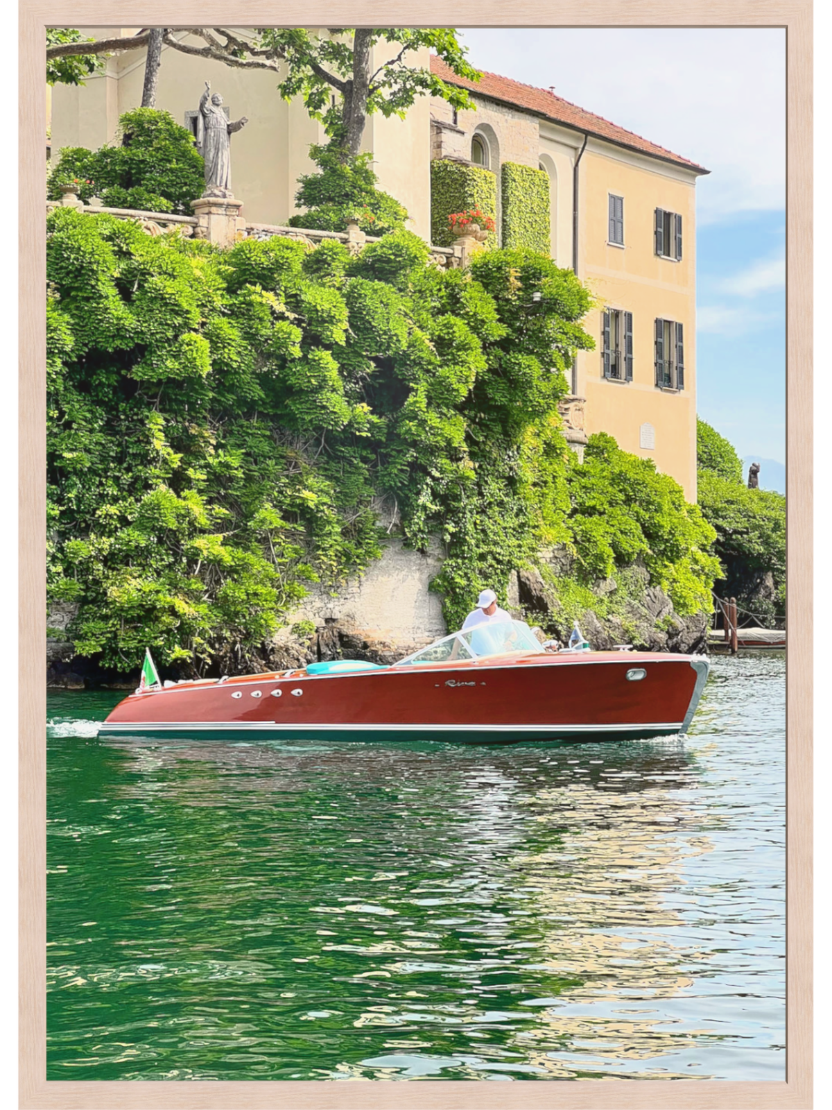 Red boat on a body of water with a building and greenery in the background