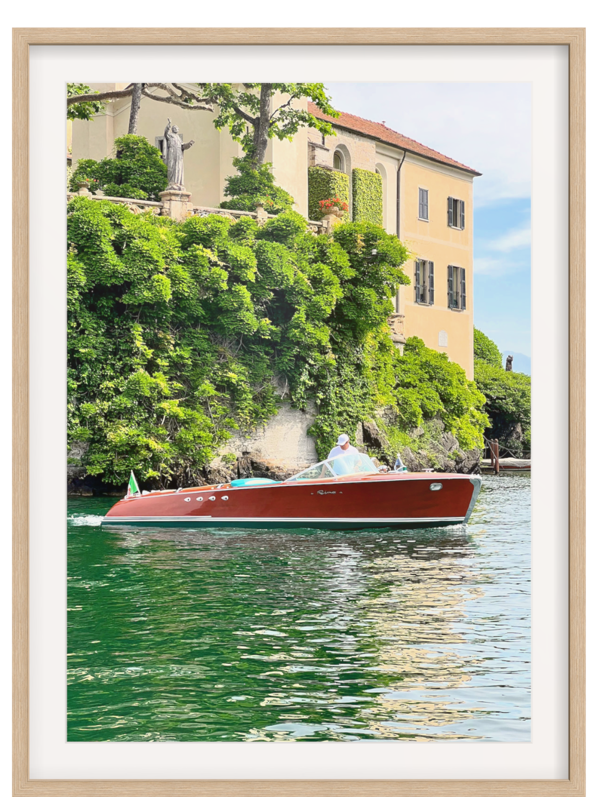 Red boat on a body of water with a building and greenery in the background