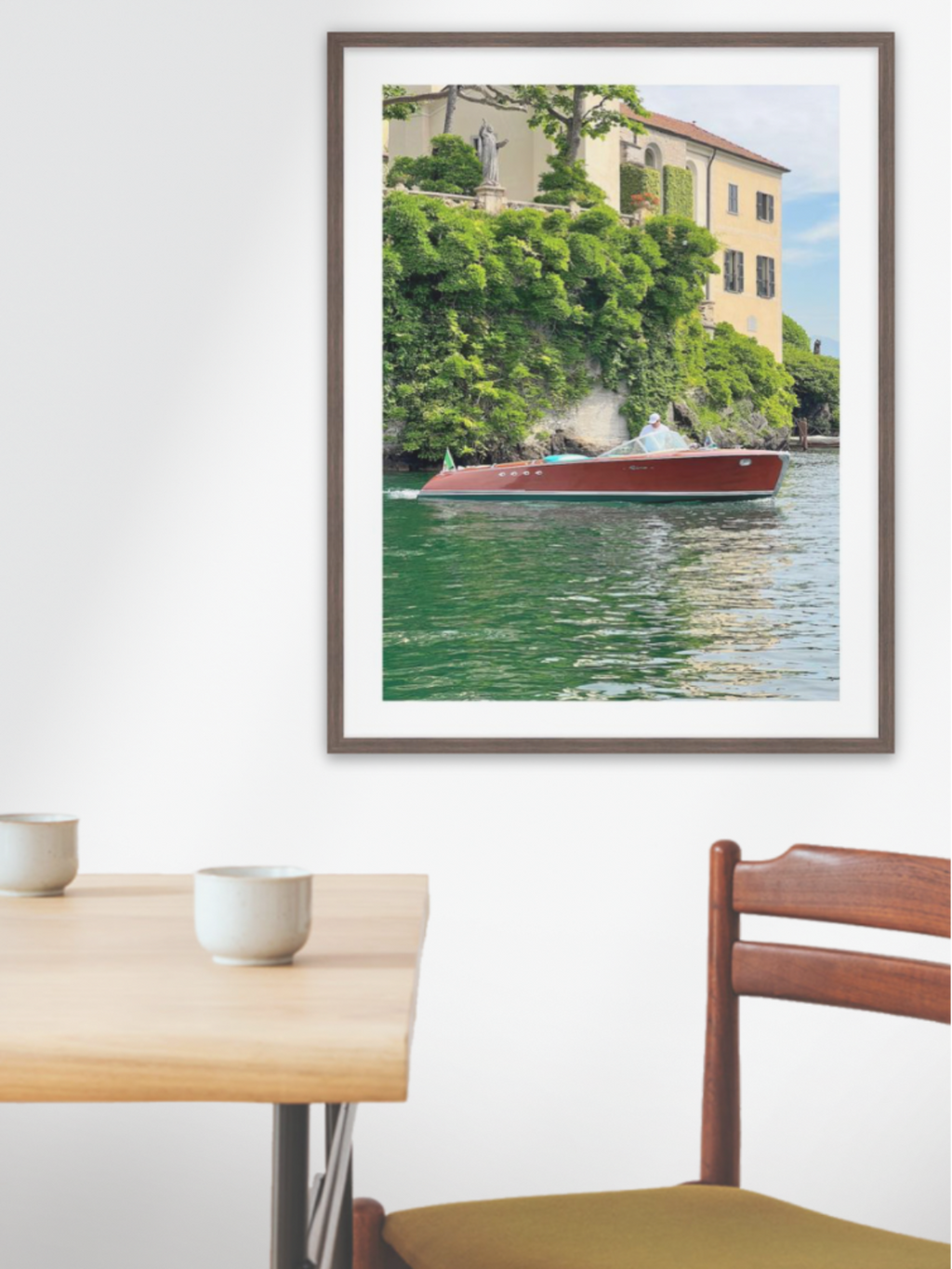 Framed photograph of a canal scene with a boat on a wall above a dining table.