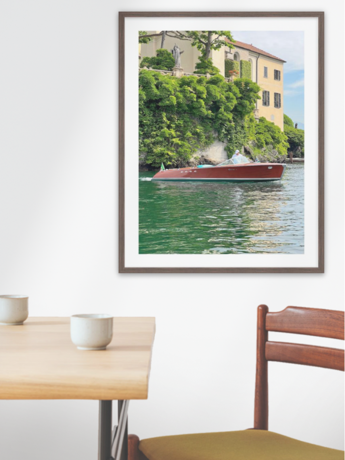 Framed photograph of a canal scene with a boat on a wall above a dining table.