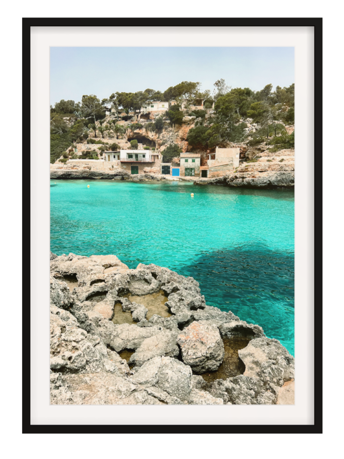 Framed photograph of a coastal scene with turquoise water and rocky shoreline.black frame with border