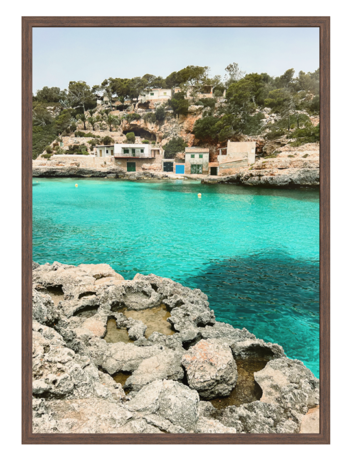 Coastal scene with turquoise water and rocky shore, framed picture. chocolate frame