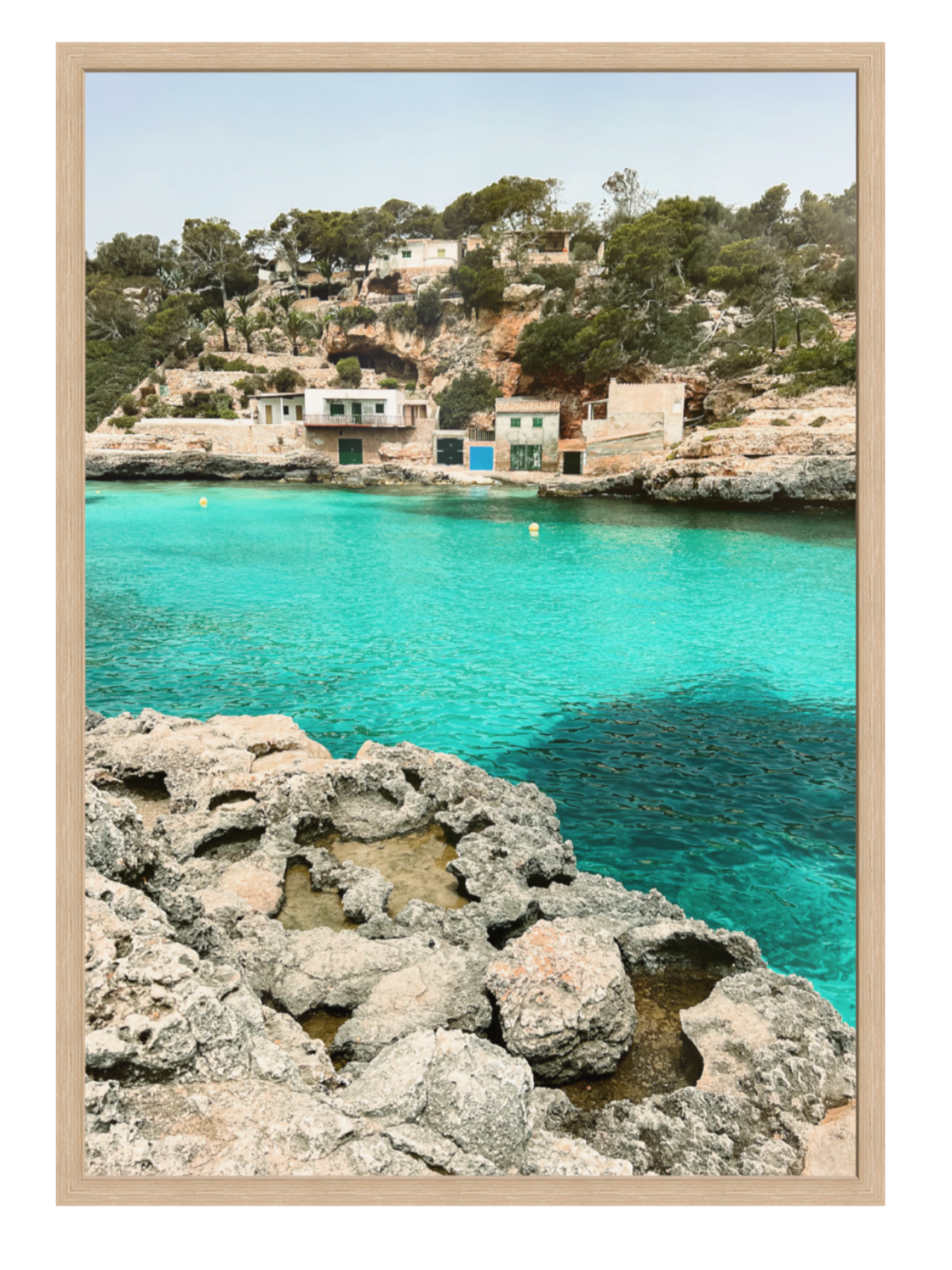 Coastal scene with turquoise water and rocky shore, framed as a print. oak frame