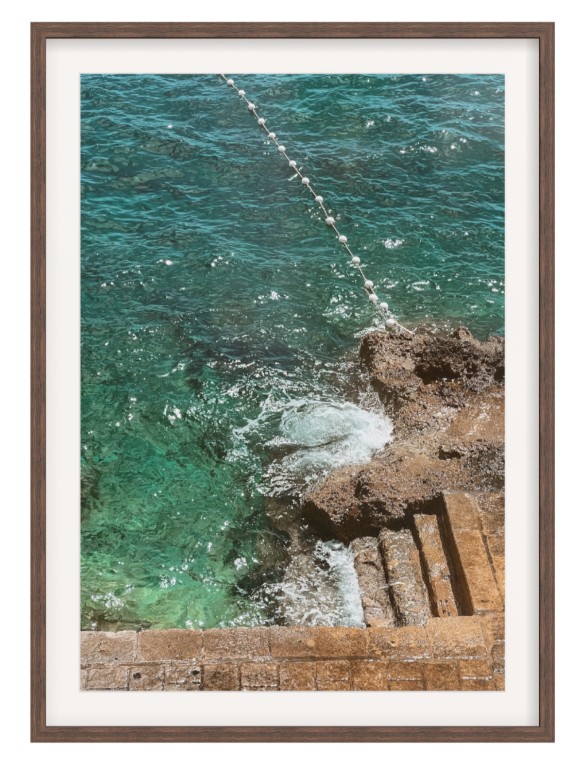 Framed artwork of a coastal scene with turquoise water and rocky shoreline. chocolate frame with border